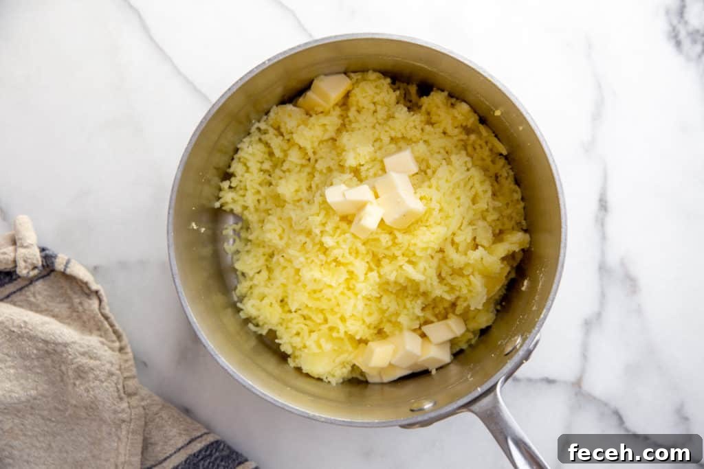 Riced potatoes in a pot with cubes of butter on top. 
