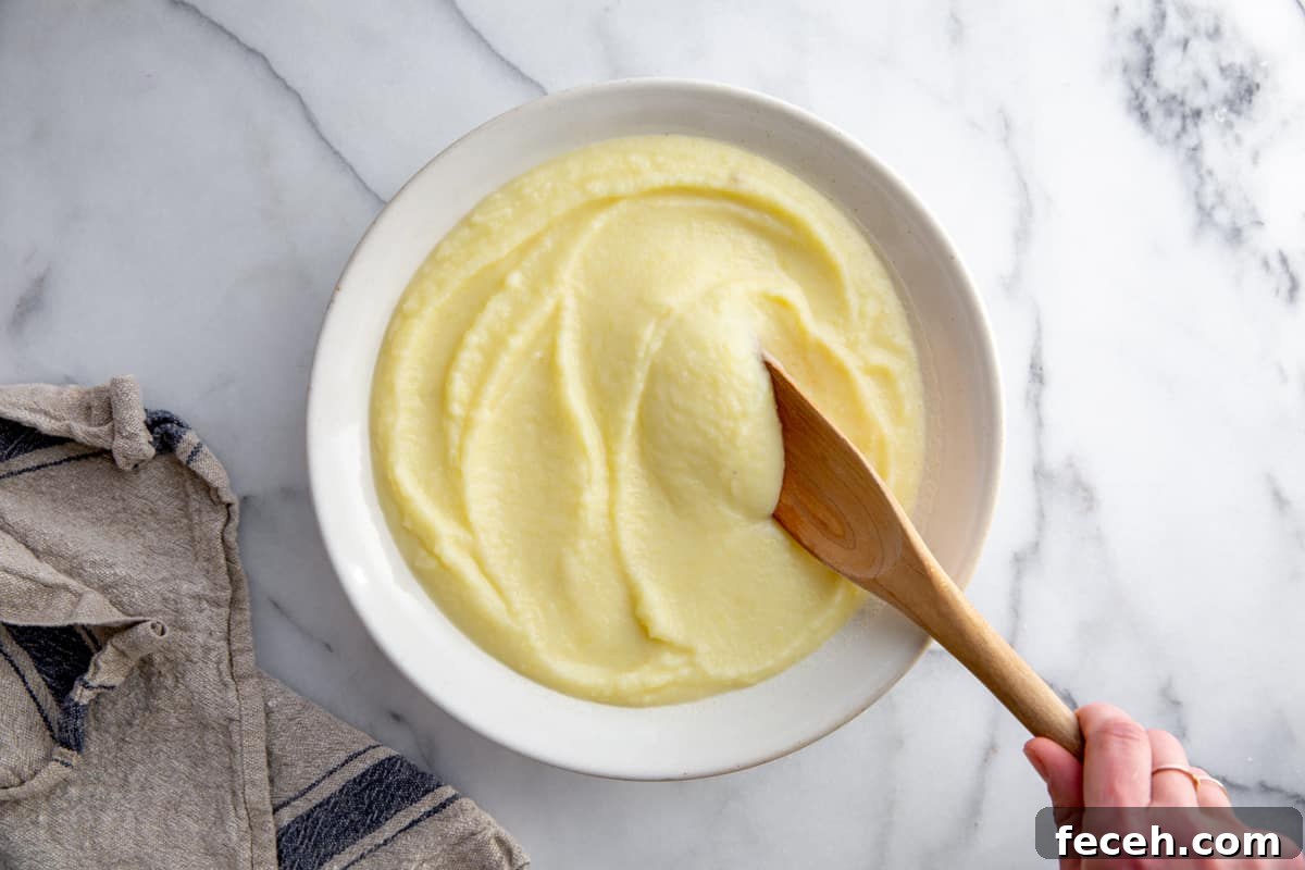 The homemade pomme puree in a serving bowl with a wooden spoon. 