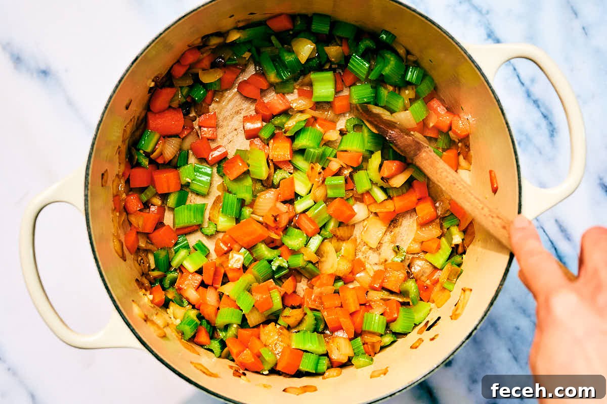 Vegan Italian Wedding Soup Recipe with Plant-Based Meatballs 10 Onion, carrots, celery, and garlic being sauteed in a pot for soup.