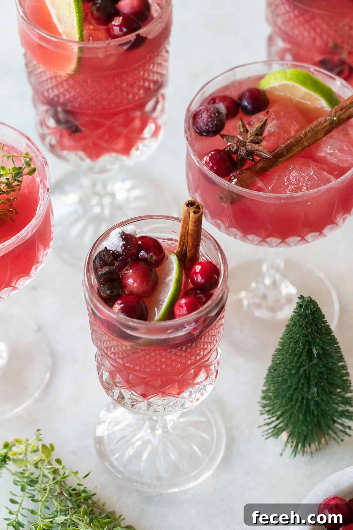 Festive Nonalcoholic Christmas Punch Recipe for Holiday Parties 4 Mocktail with cranberry juice and cinnamon in vintage glasses.