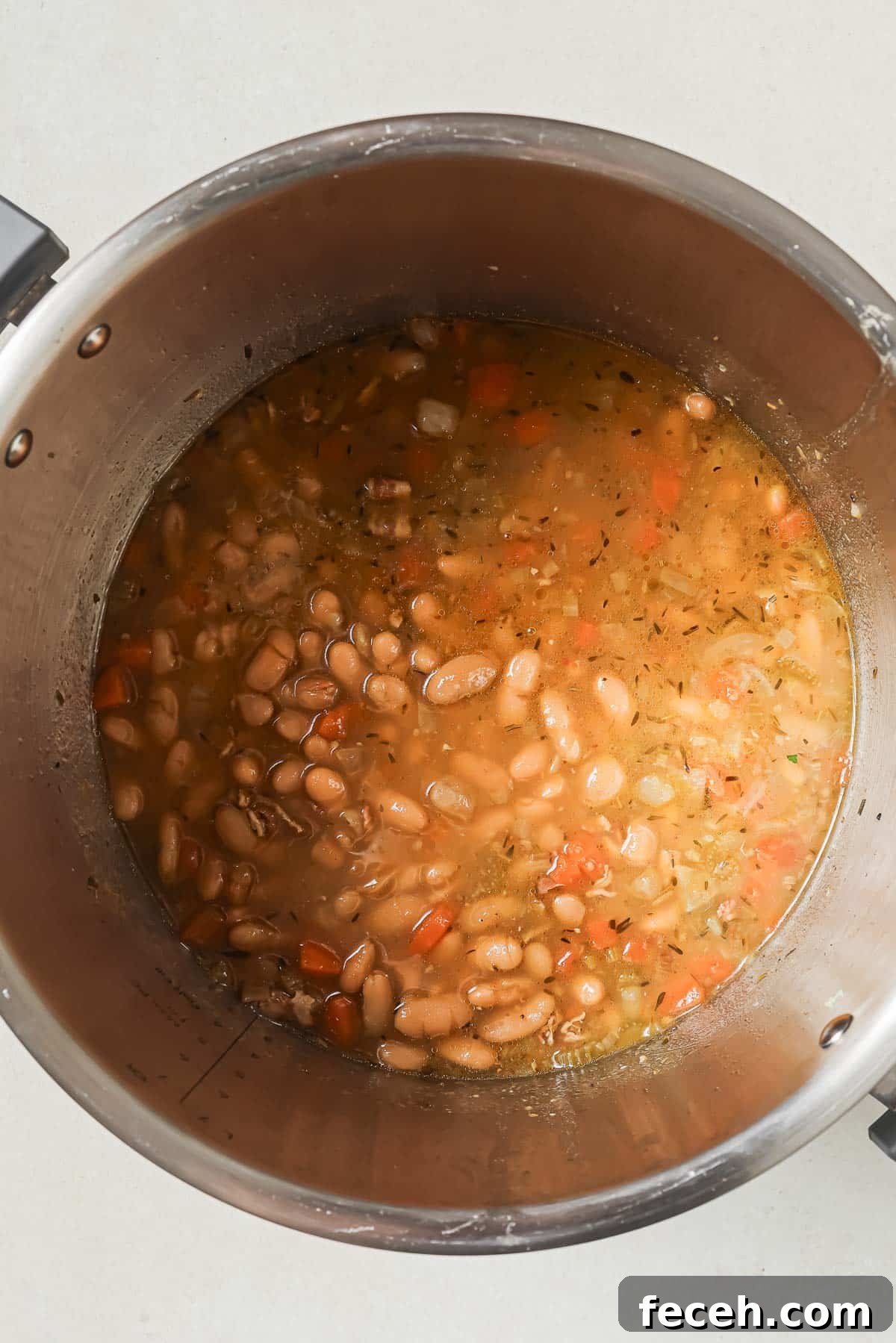 Instant Pot Navy Bean Soup Recipe for Creamy, Hearty Comfort 11 A Instant pot containing cooked navy beans and diced vegetables with broth.