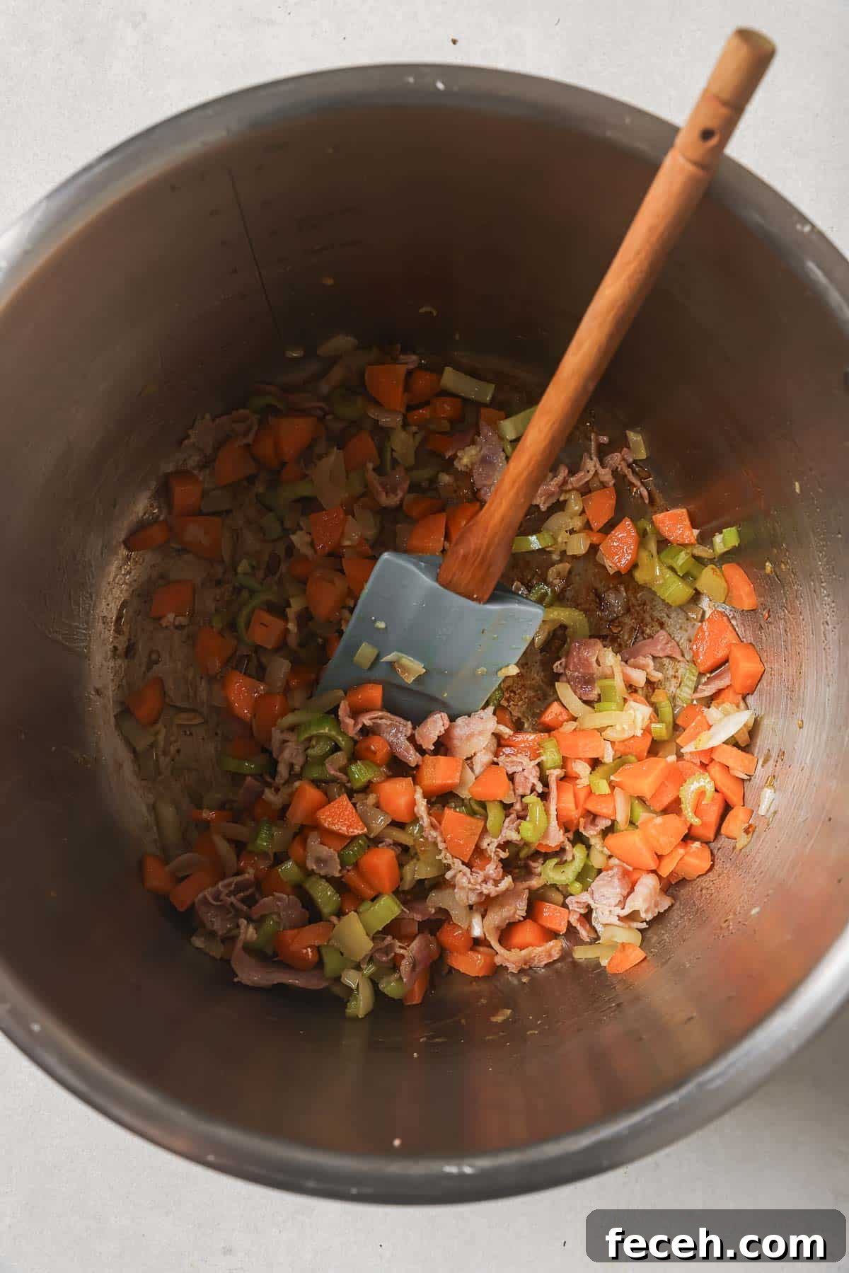 Instant Pot Navy Bean Soup Recipe for Creamy, Hearty Comfort 8 Chopped carrots, celery, and onion in a metal Instant pot with a wooden spatula.