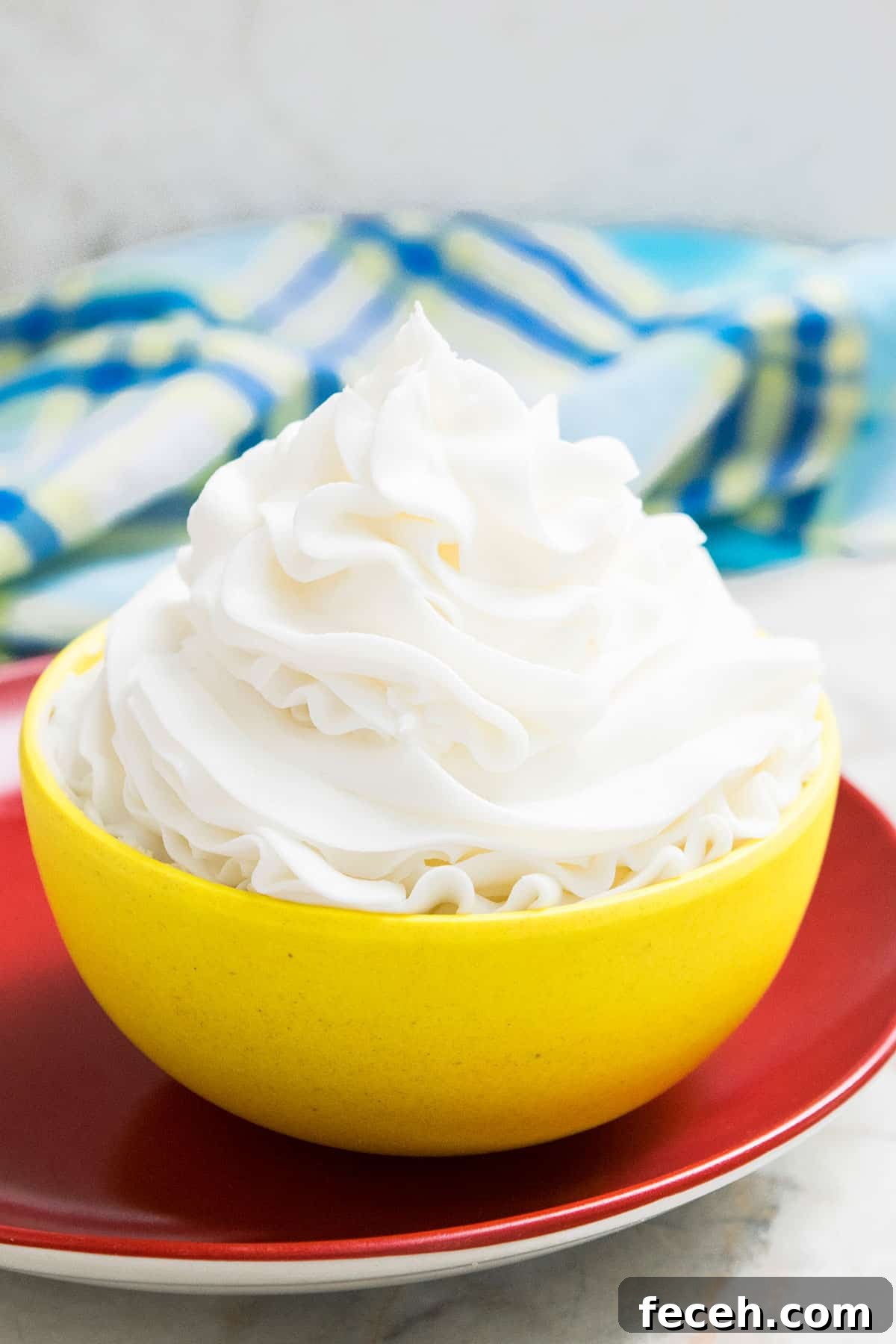 Best Easy Classic American Buttercream Frosting in Yellow Bowl on Red Dish.