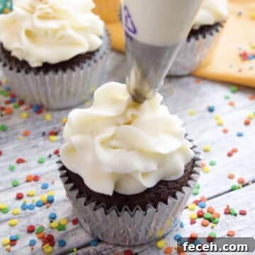 Piping white icing on top of cupcake.