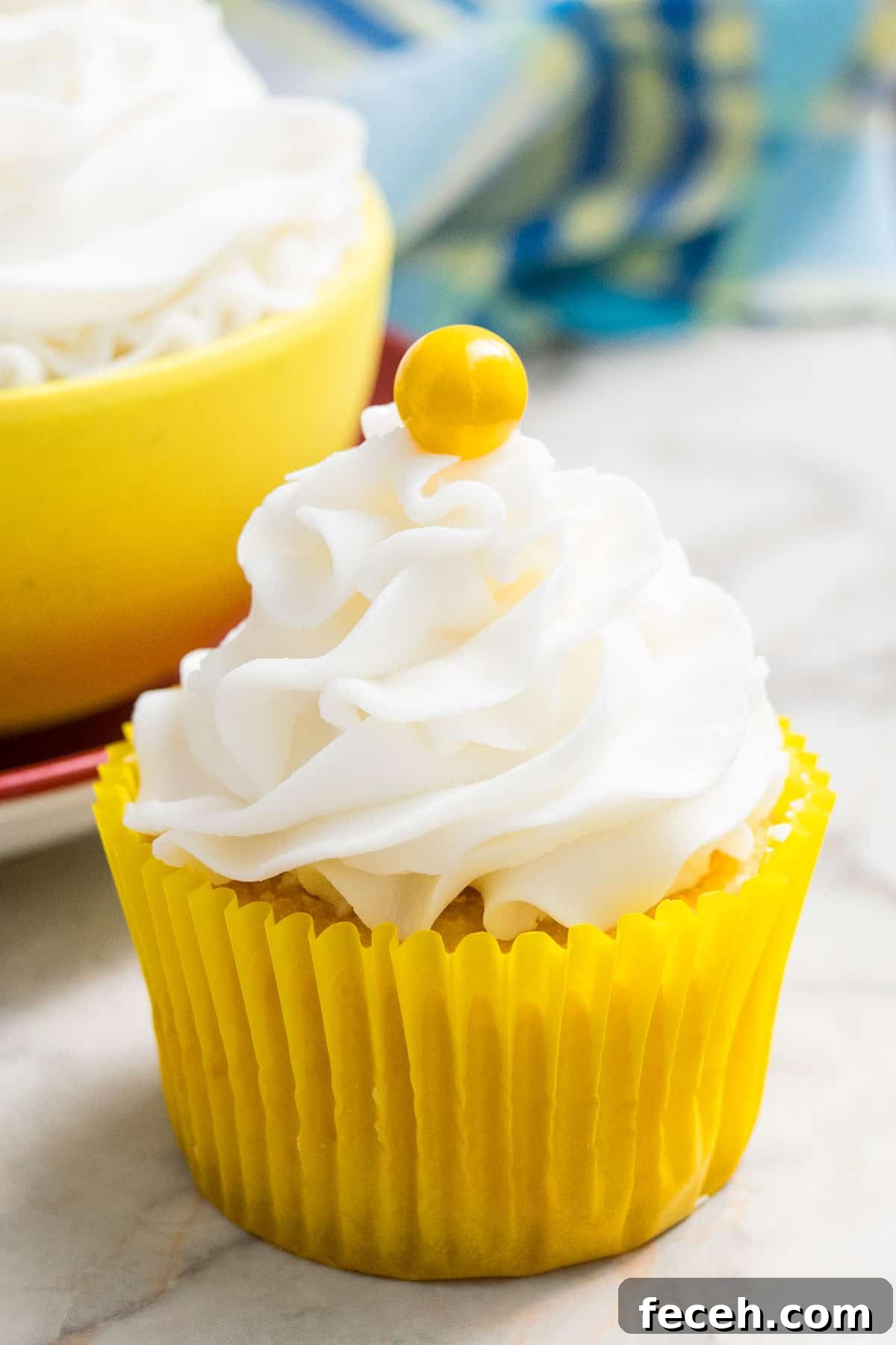 Frosted Cupcake With Yellow Candy Decoration on Marble Background.
