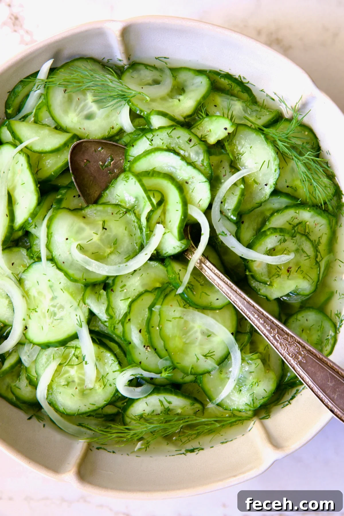 Cucumber Onion Salad in serving bowl with serving spoon.