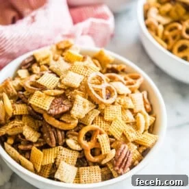 gluten free chex mix in a bowl on a marble board with a red and white striped napkin sitting behind it