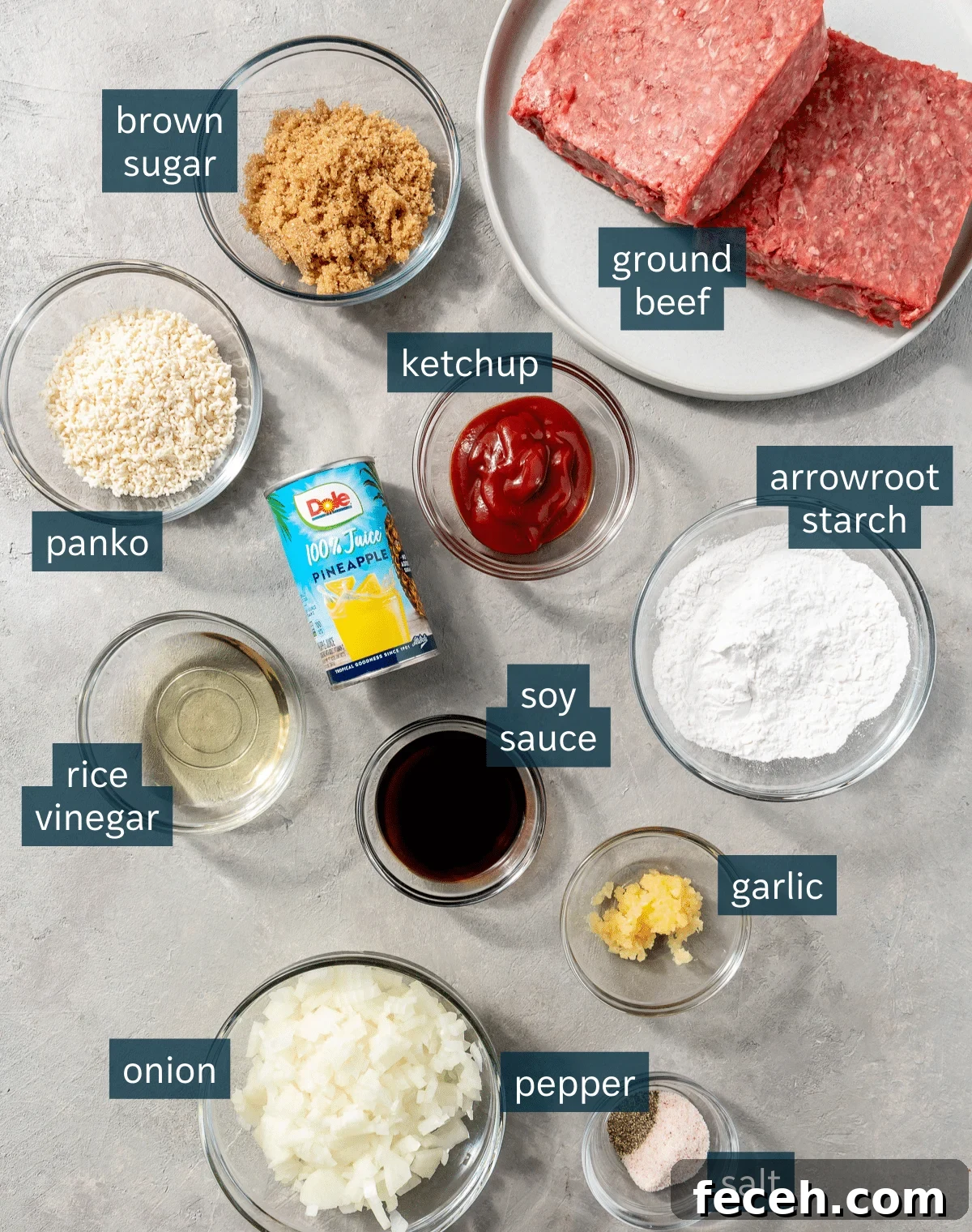 Ingredients for sweet and sour meatballs sit in a variety of glass bowls on a grey countertop.