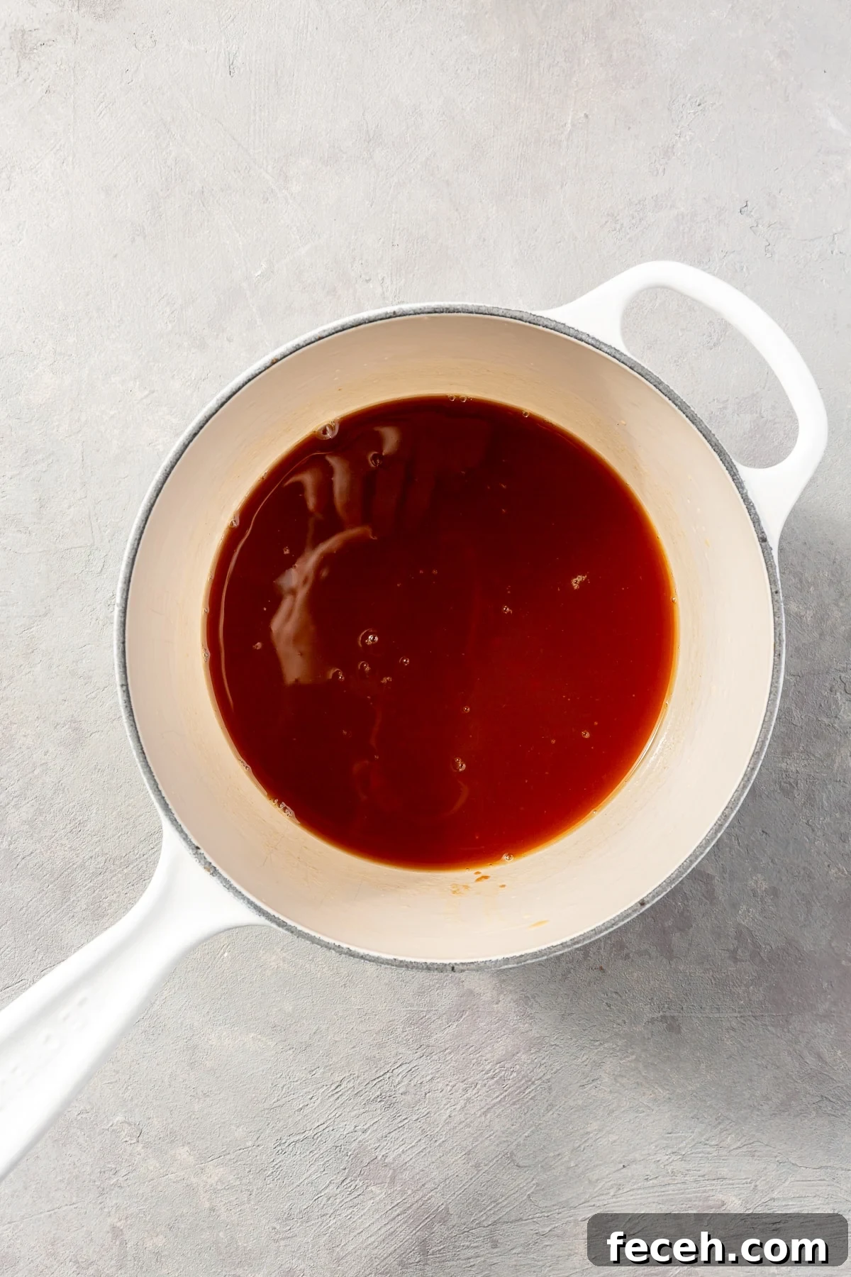 A dark red liquid sits in the bottom of a white pot.