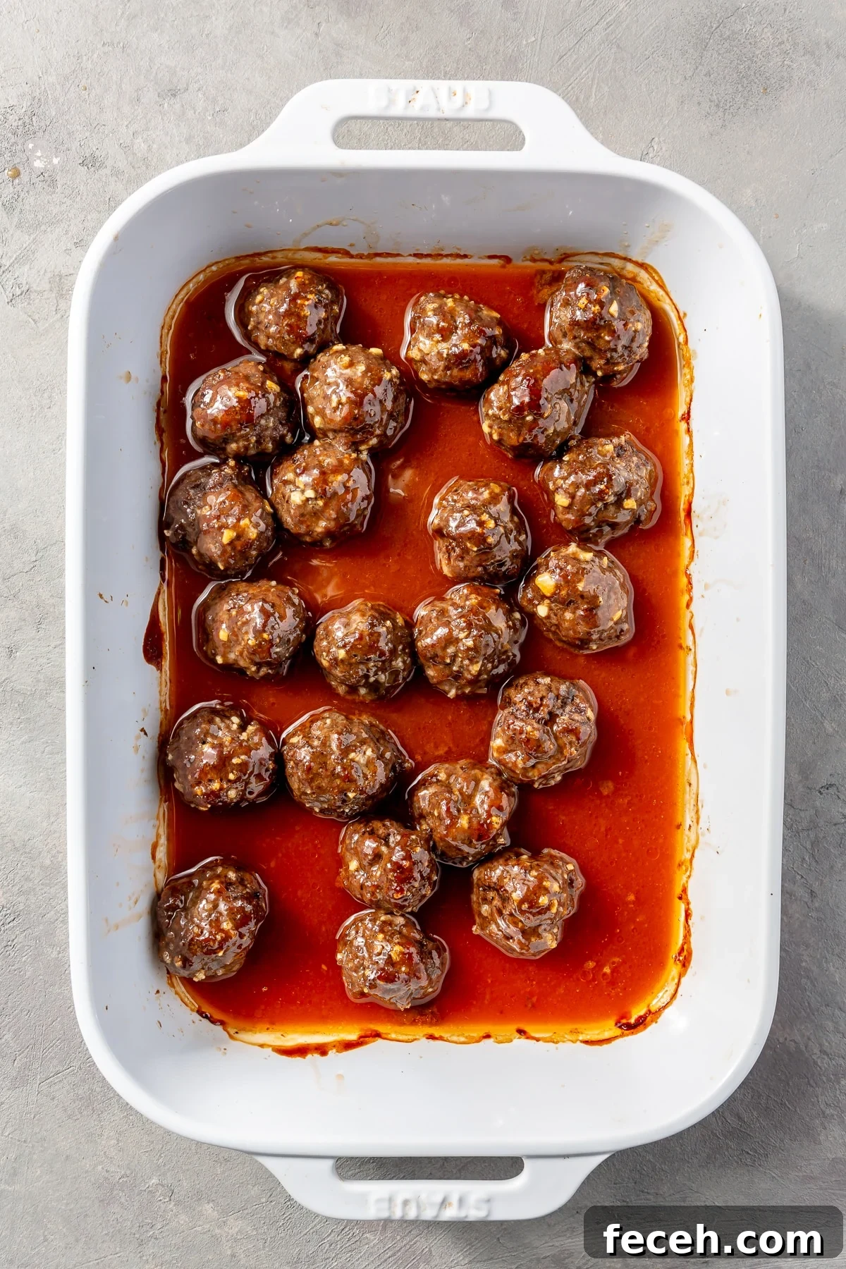Fully baked meatballs sit in a white baking dish.