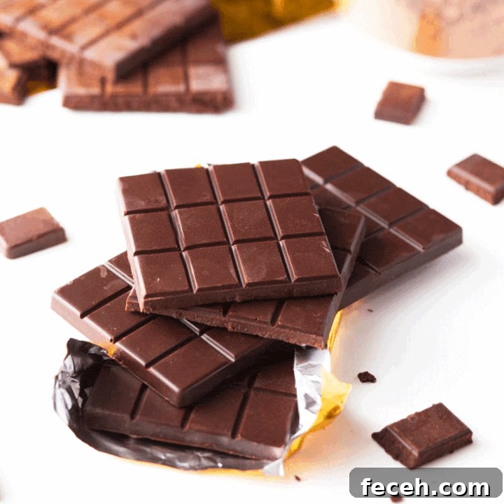 A stack of homemade chocolate bars with cocoa powder and a gold foil wrapper in the background
