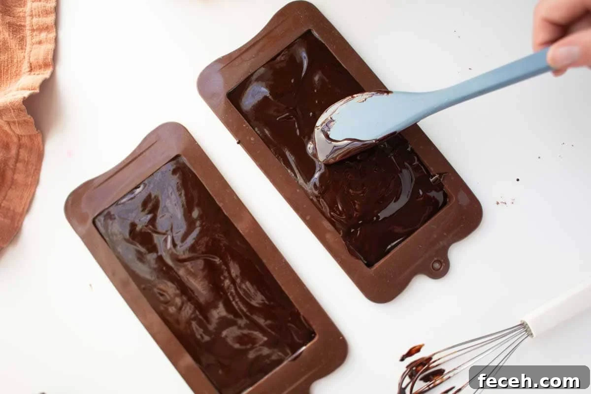 Homemade Dark Chocolate Bar Recipe: Rich, Smooth, & Simple 7 Melted chocolate being spread into chocolate bar molds with a spatula