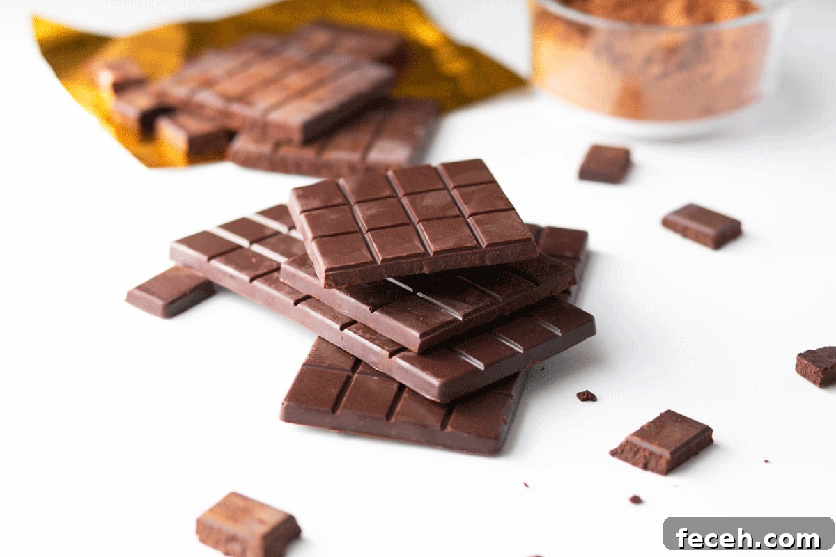 Homemade Dark Chocolate Bar Recipe: Rich, Smooth, & Simple 9 A stack of homemade chocolate bars with cocoa powder and a gold foil wrapper in the background