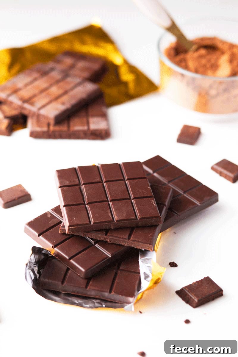 Homemade Dark Chocolate Bar Recipe: Rich, Smooth, & Simple 10 A stack of homemade chocolate bars with cocoa powder and a gold foil wrapper in the background