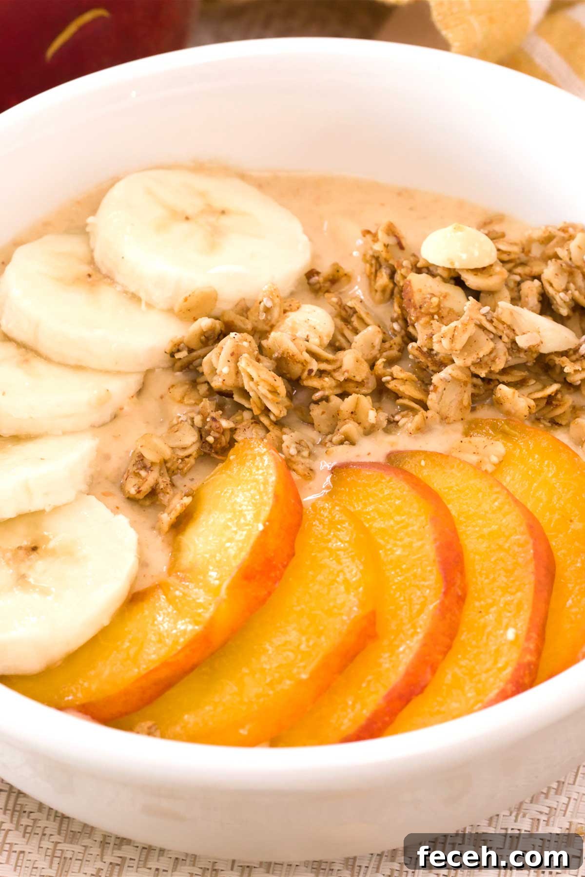 Peach Banana Smoothie Bowl topped with Vanilla Almond Granola 3 Close-up of a peach banana smoothie bowl with sliced peaches, bananas, and vanilla granola.