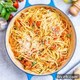 Cooked spaghetti fully coated in tomato basil sauce, ready to serve from a round deep skillet.