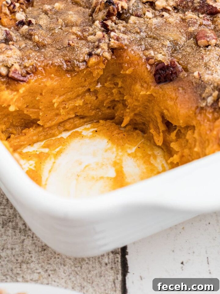 Close up of a corner of a dish of sweet potato casserole with a scoop missing.
