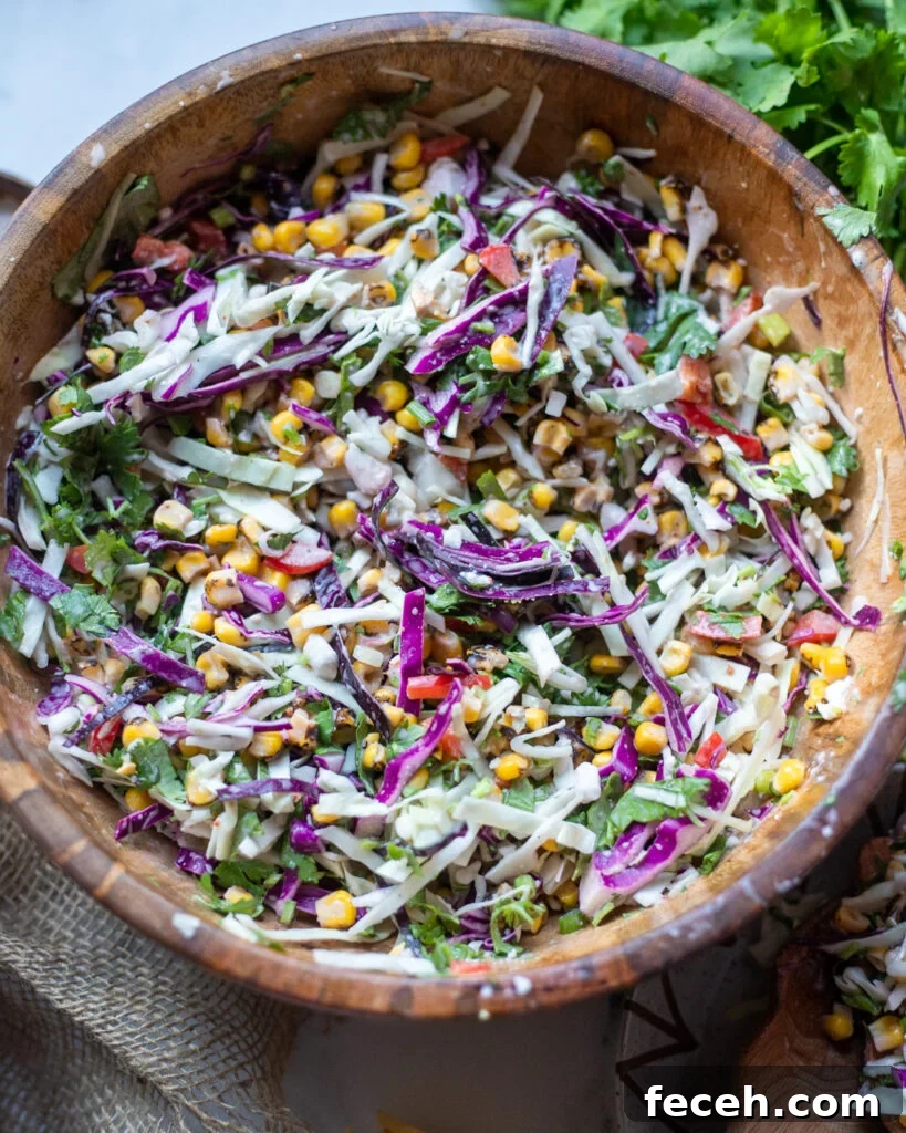 overhead view of a wooden serving bowl with vegan street corn slaw with cabbage and vegan cheese.