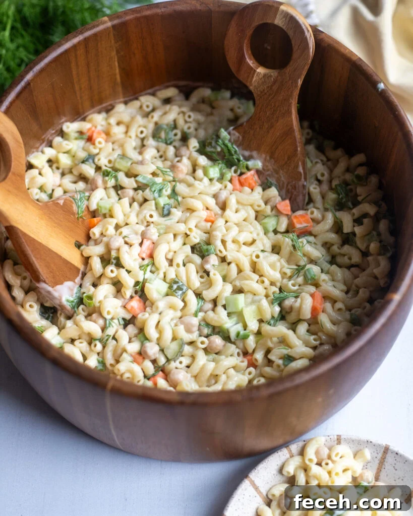 overhead view of a wooden serving bowl with non-dairy dill pickle pasta salad made with creamy non-dairy yogurt and lots of pickles.