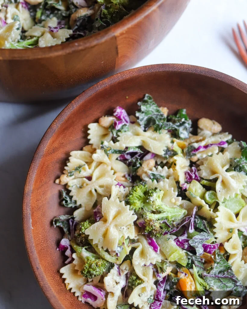 overhead view of vegan caesar pasta salad in a wooden serving bowl with cabbage, roasted broccoli, and white beans.