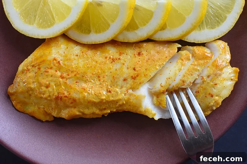An overhead shot of Tandoori Fish on a plate with sliced lemons.