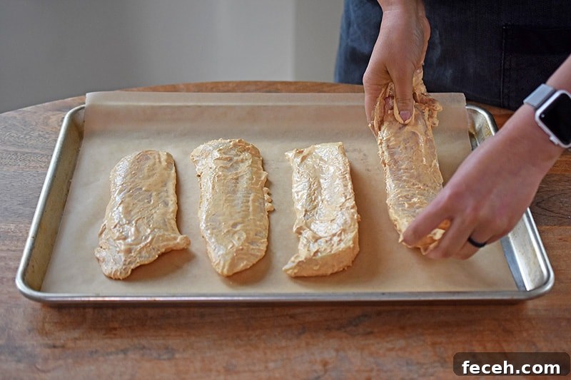 Four pieces of Tandoori Fish are placed on a parchment lined rimmed baking sheet.