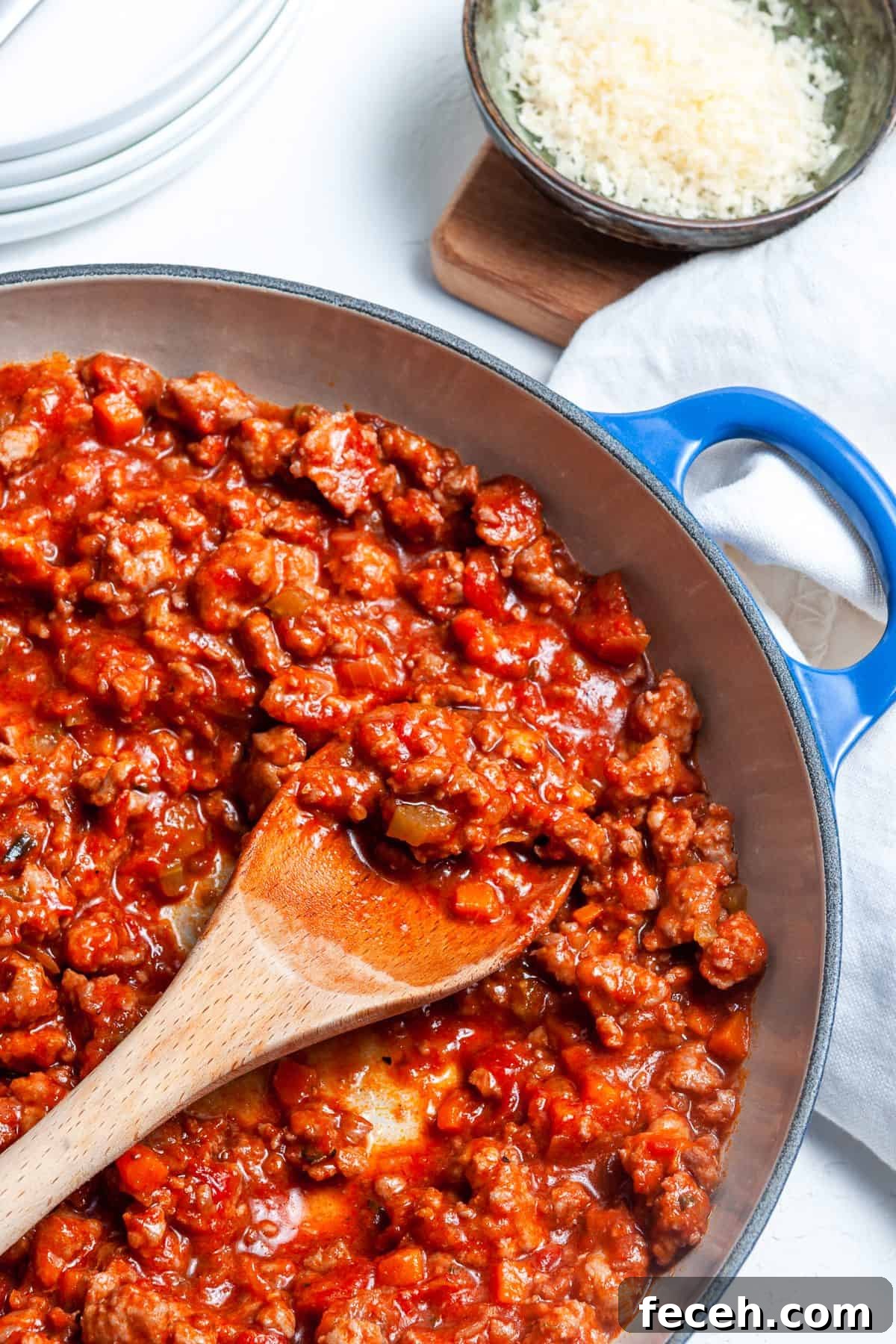 Wooden spoon, scooping some ragu from the dish.