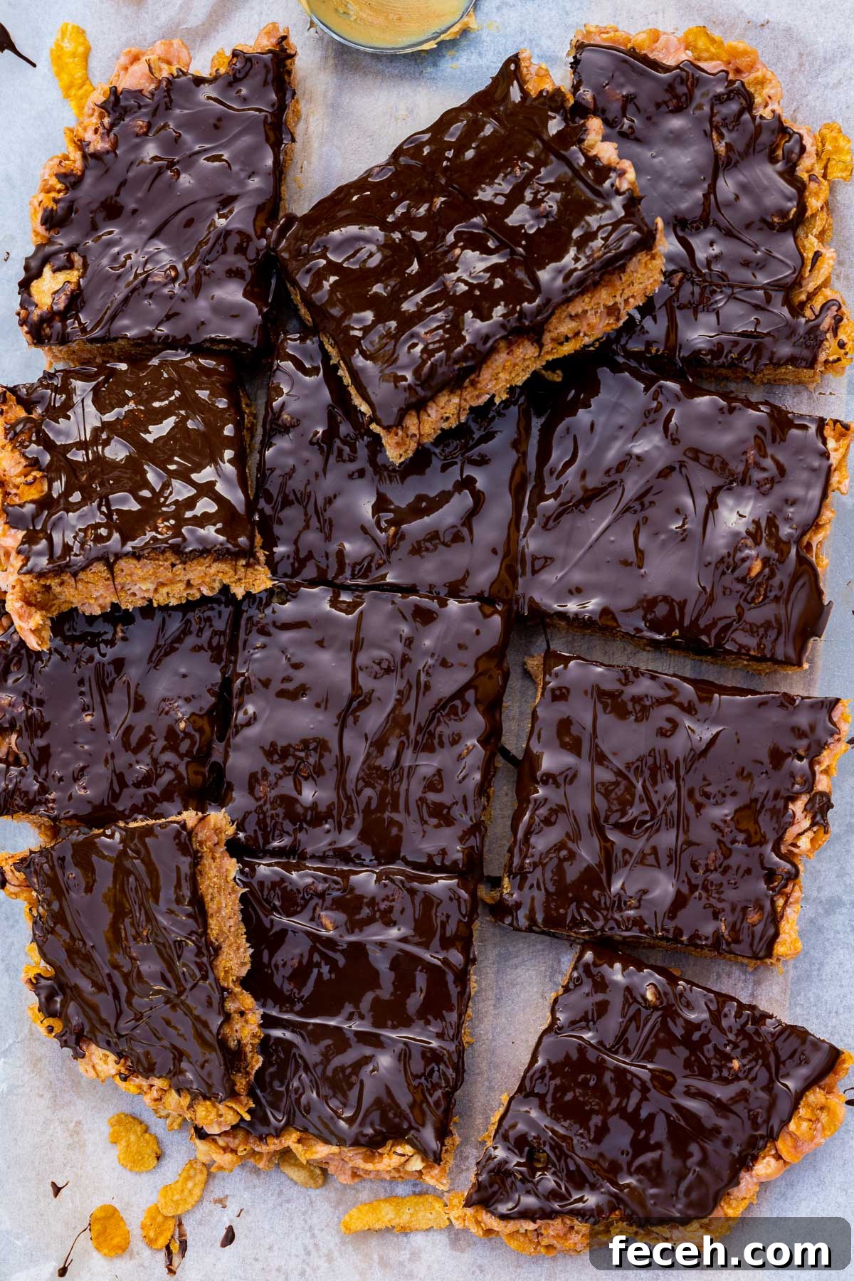 Overhead of the bars cut into squares on baking paper with a few cornflakes scattered around.