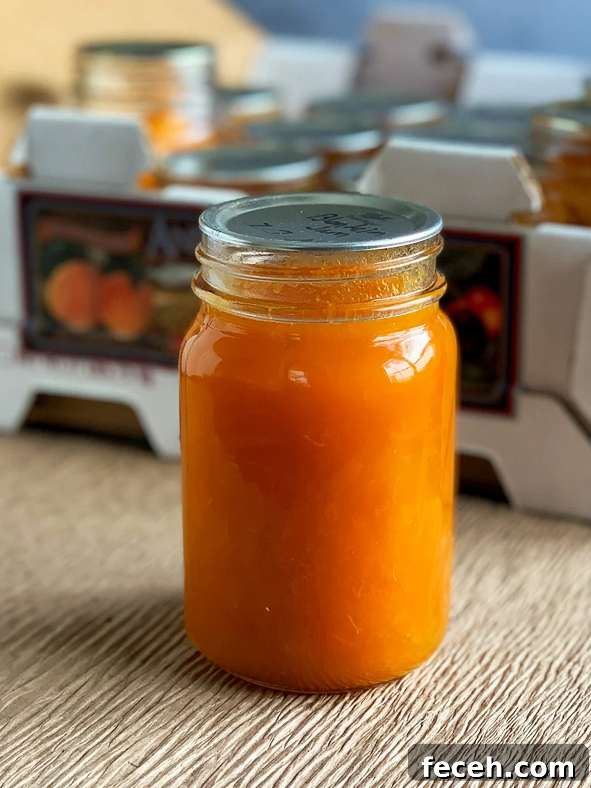 Close up of a jar of apricot jam in front of a crate of apricots.