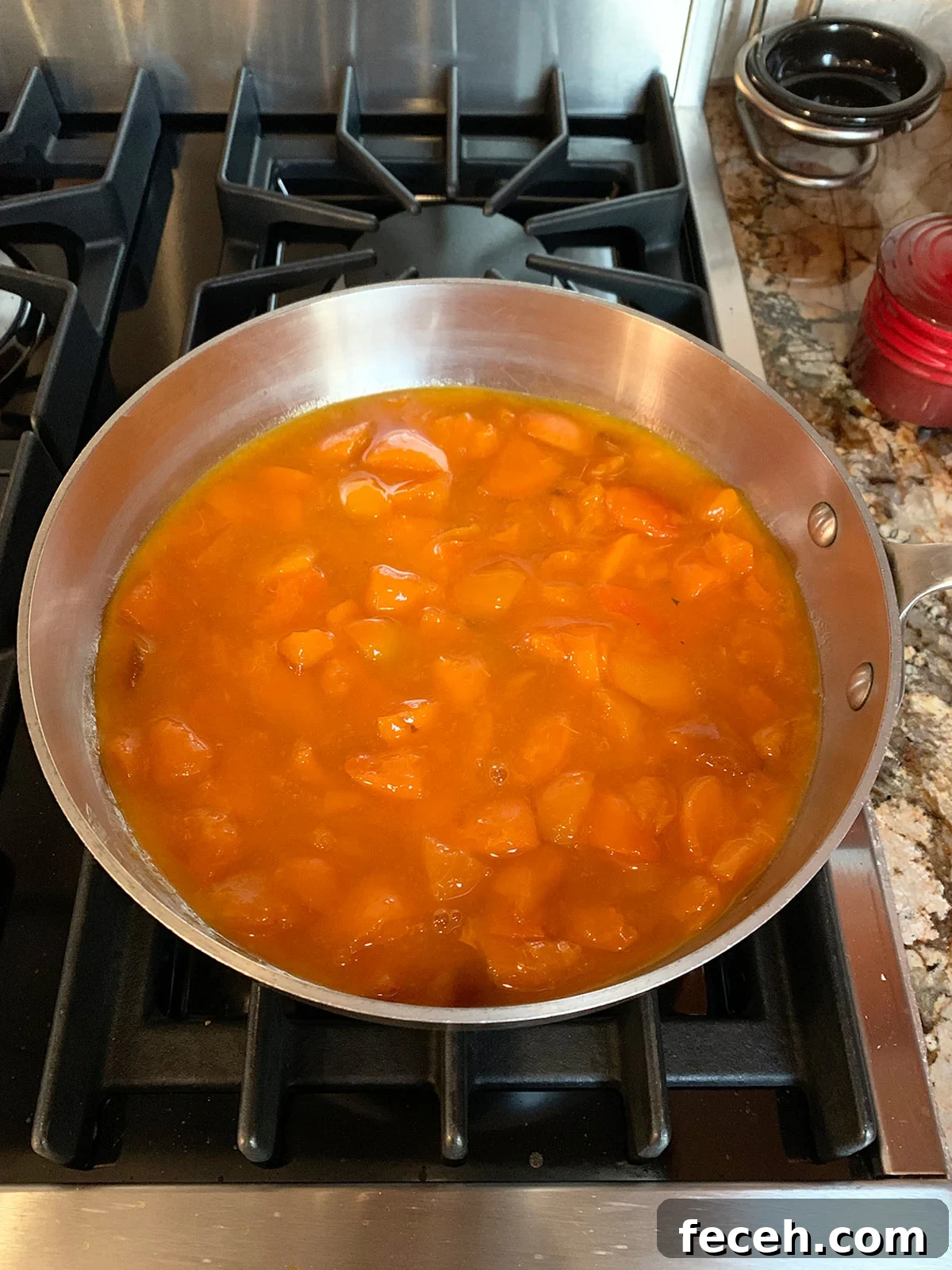 Saucepan with macerated apricot preserves starting the boiling process.