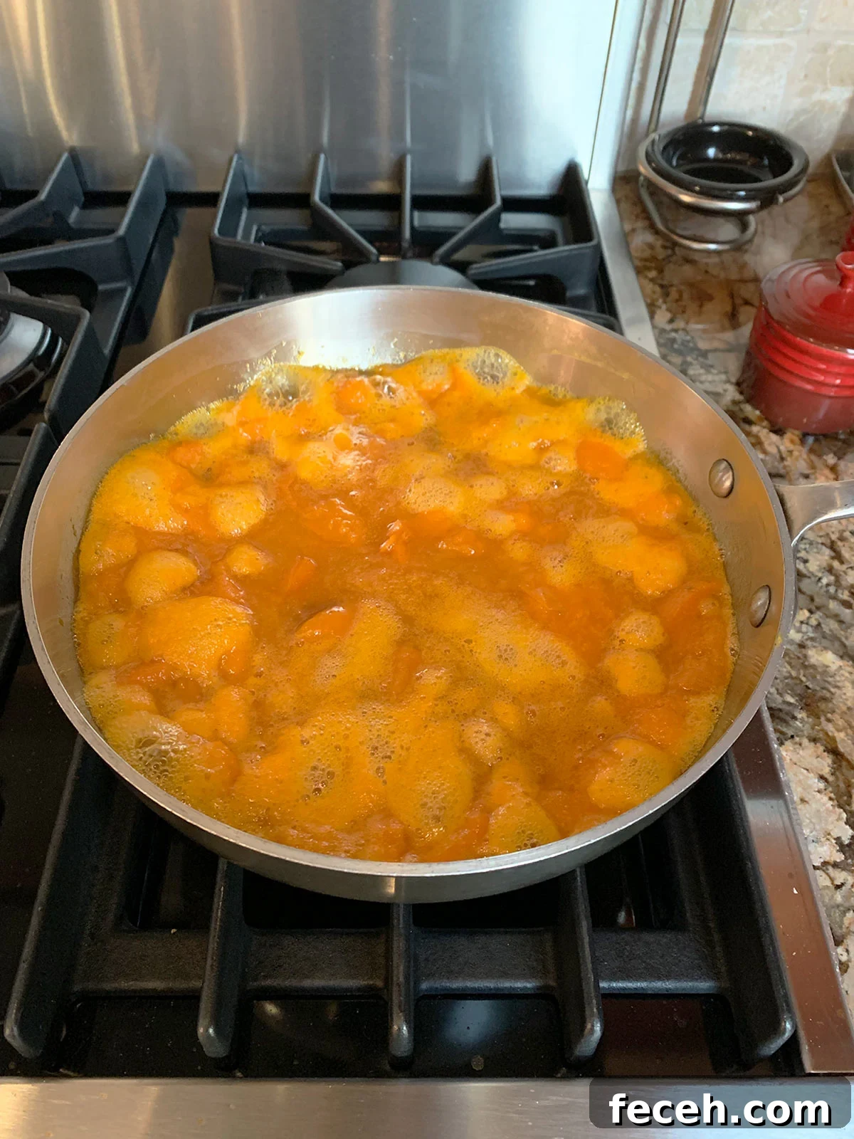 Boiling apricot mixture in pot with foam forming at the top.