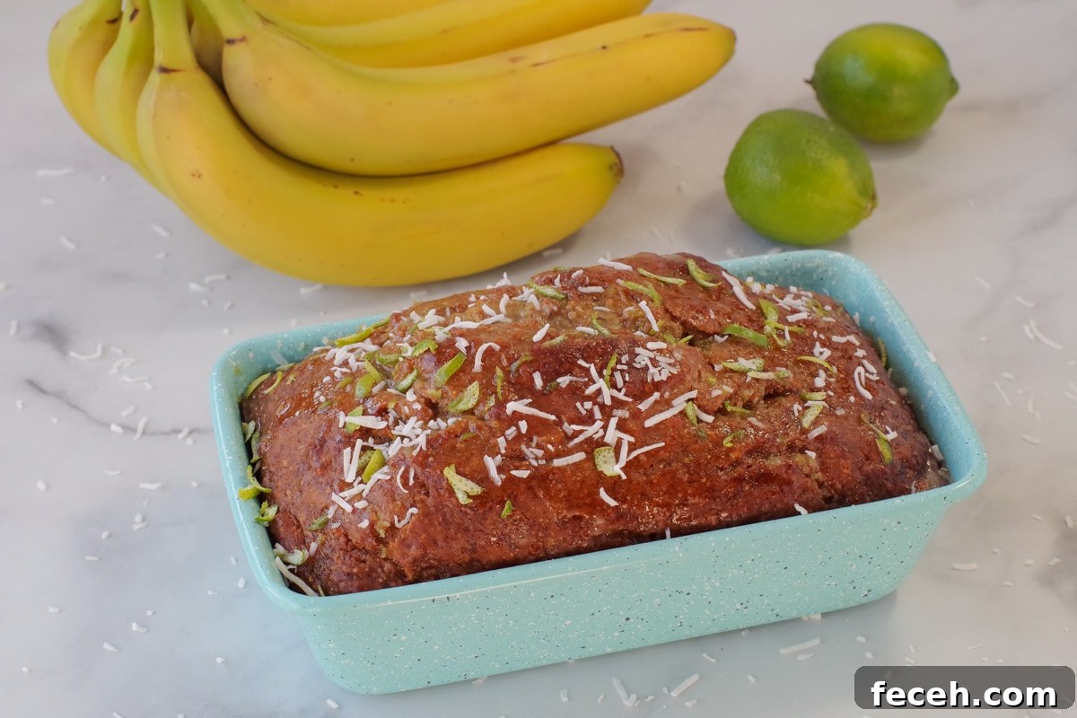Tropical banana bread in blue loaf pan with bananas and limes in background