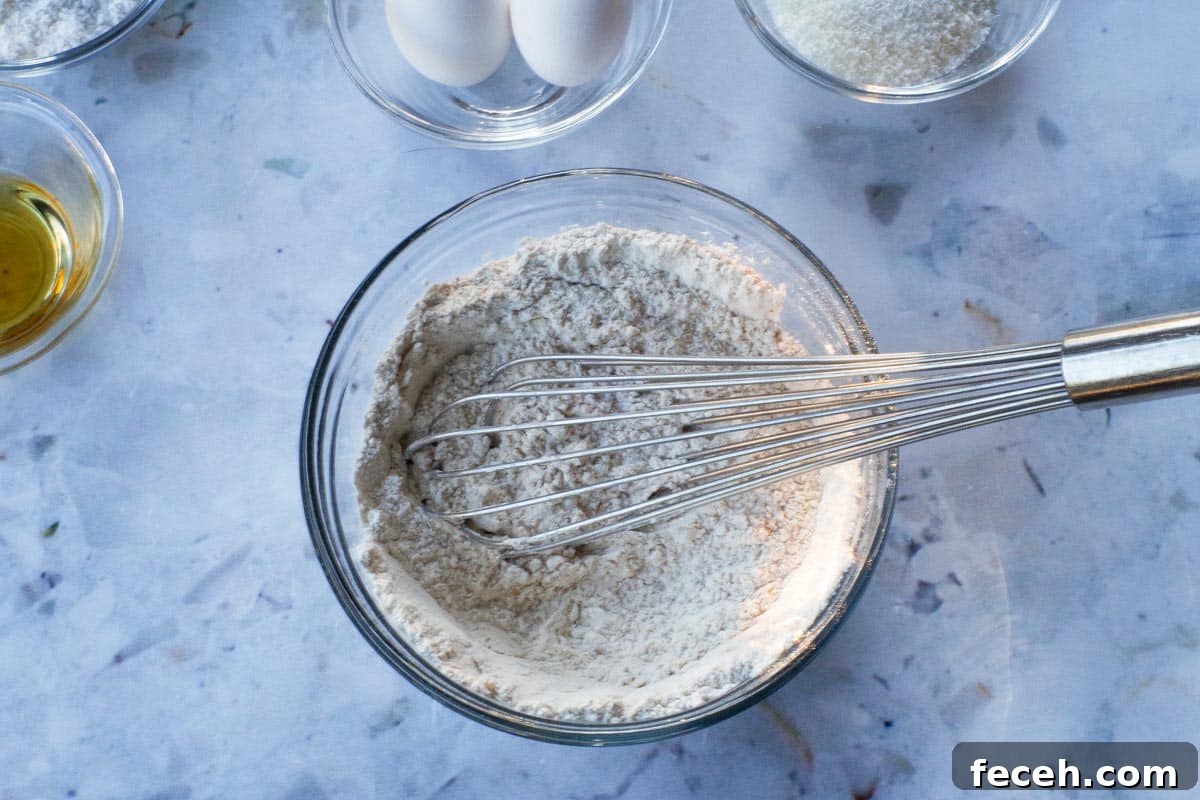 Dry ingredients for Tropical Banana Bread mixed together in glass bowl with metal whisk.