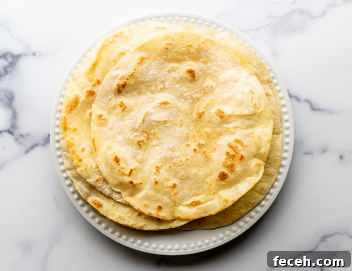 lightly browned flour tortillas stacked on a plate.