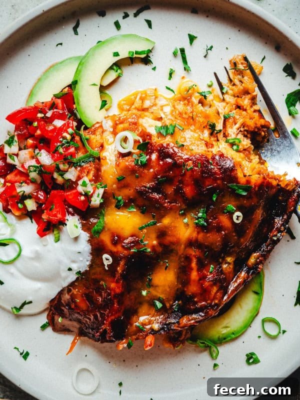 A plate with a serving of chicken enchiladas covered in melted cheese.
