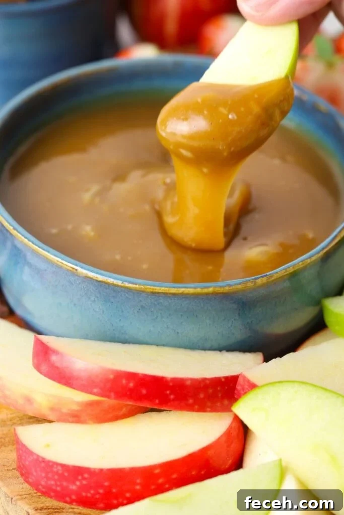 Dipping an apple into the homemade caramel dip to show the texture and how the dip stays on the apple slice.