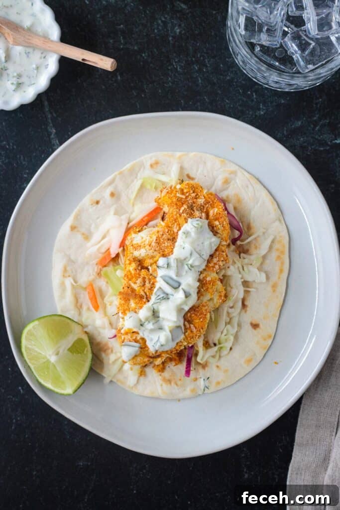 A tortilla filled with coleslaw, breaded roasted cauliflower, and topped with tartar sauce.