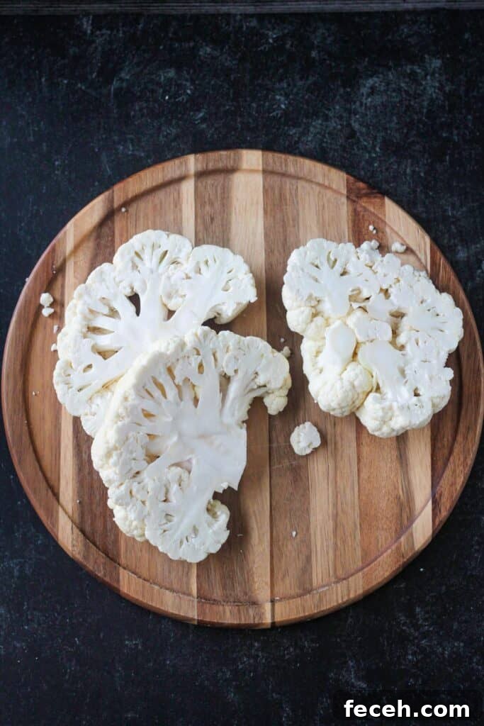 Cauliflower cut into slices on a cutting board.