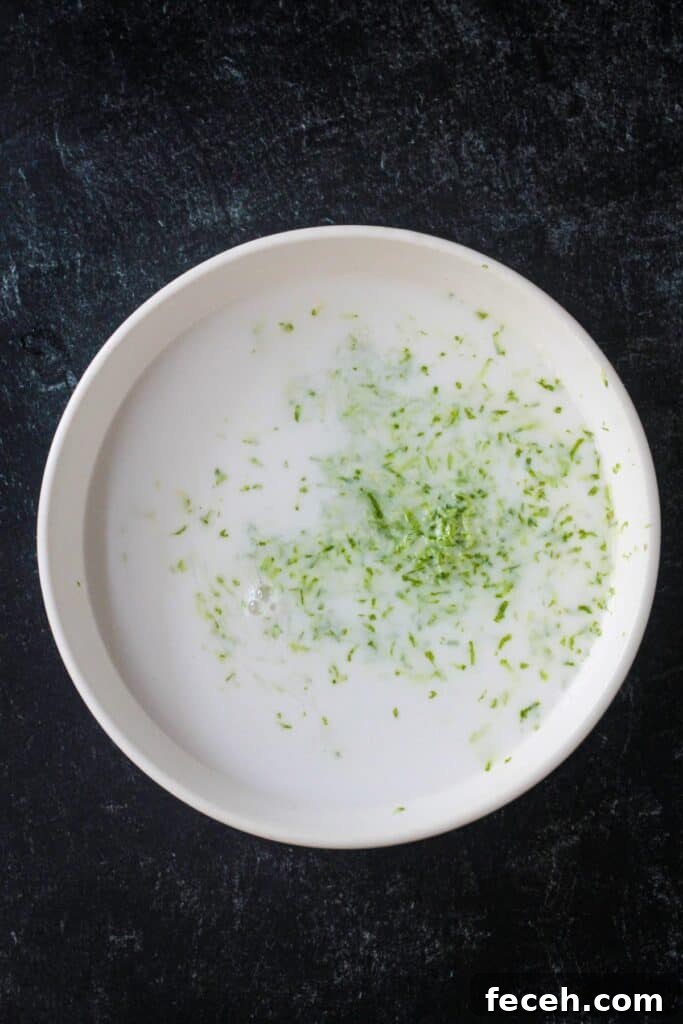 Lime zest added to coconut milk in a bowl.