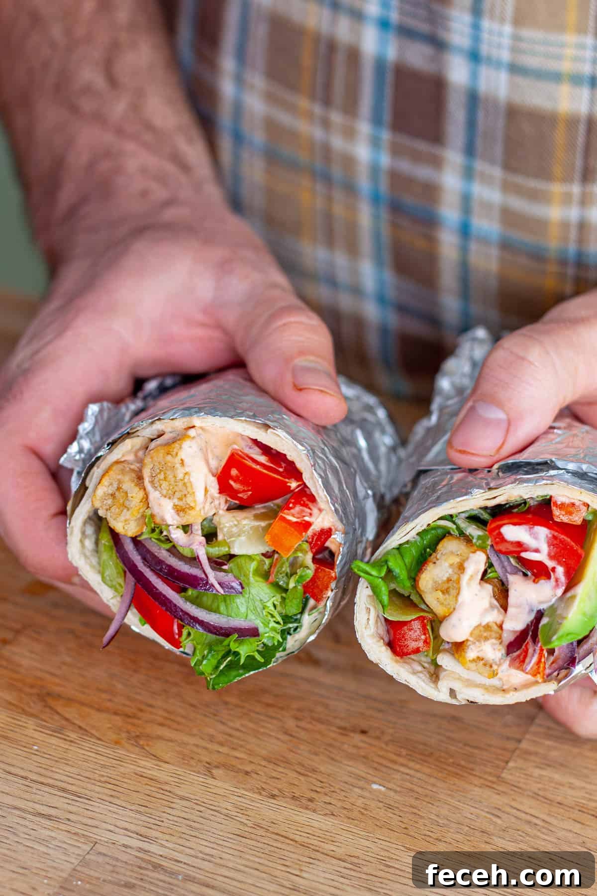 Hands holding crispy buffo tofu wraps cut in half.